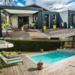 Piscine, terrasse et façade de la maison visibles sur la même photo d’une propriété à vendre
